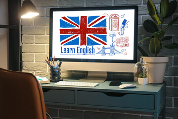 Modern computer with flag of Great Britain and text LEARN ENGLISH on screen at workplace in evening - obrazy, fototapety, plakaty