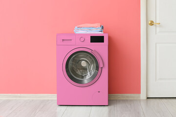 Pink washing machine near color wall