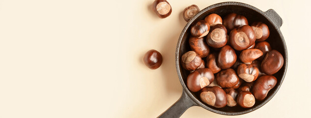 Frying pan with chestnuts on light background with space for text
