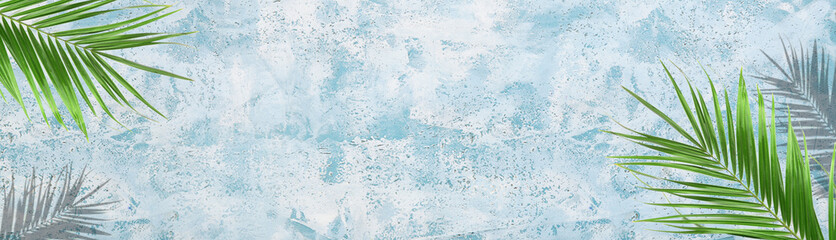 Green tropical leaves on blue grunge background with space for text. Banner for design