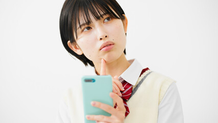 スマートフォンを持って困惑する女子高校生