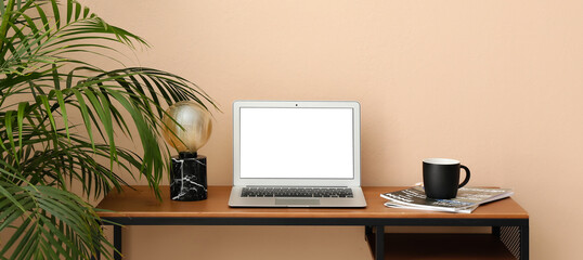 Workplace with modern laptop near beige wall