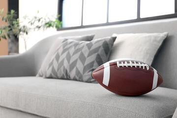 Rugby ball on comfortable sofa in living room, closeup