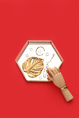 Stand with golden jewelry and wooden hand on red background