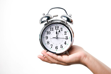 Hand holding alarm clock isolated on white background. Vintage watch in woman's hand, close up.