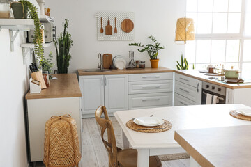 Interior of light kitchen with stylish counters, kitchenware and pegboard on white wall