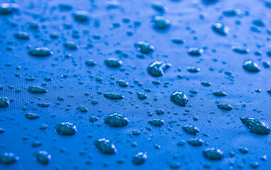 Close-up of raindrops on a blue canvas. atmosphere after the rain.