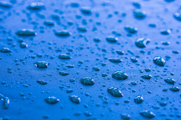 Close-up of raindrops on a blue canvas. atmosphere after the rain.