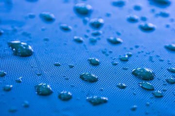 Close-up of raindrops on a blue canvas. atmosphere after the rain.