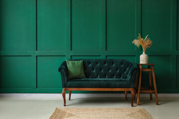 Stylish sofa near green wall