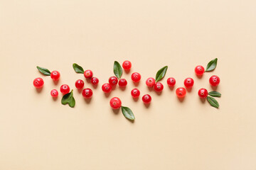 Ripe lingonberries with leaves on beige background