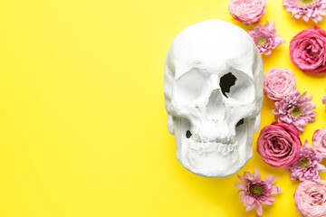 Human skull with flowers on yellow background