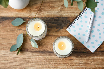 Holders with burning candles and eucalyptus leaves on wooden background