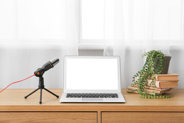 Modern laptop and microphone on table in studio