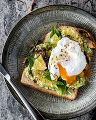 High angle view of food on a table.  Porched egg and guacamole on a toast.  Open sandwich.