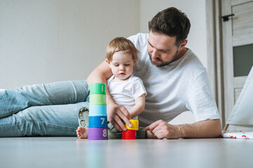 Happy father young man and baby girl little daughter having fun playing with toy in children room...
