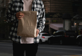 person carrying paper package with delivered food