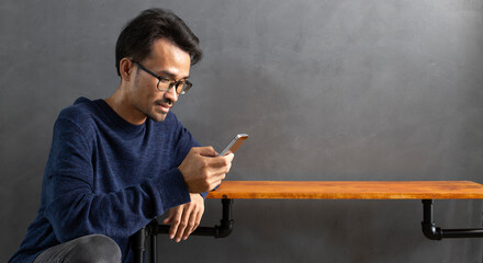man using mobile phone with empty wooden and gray wall loft copy space background