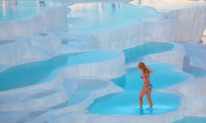Young girl is walking on the travertines - Natural travertine pools and terraces in Pamukkale....