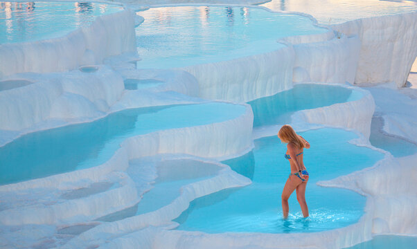 Young girl is walking on the travertines - Natural travertine pools and terraces in Pamukkale. Cotton castle in southwestern Turkey