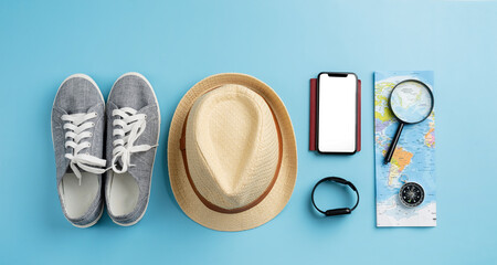 Top view travel accessories with shoes, map, smartphone with mockup screen, hat. Tourist essentials.