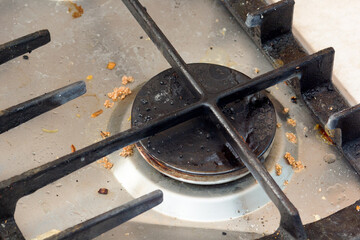 Dirty metallic surface of gas stovetop with burner cap and grate