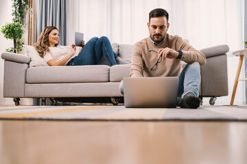 Couple spending afternoon by using technologies at home.