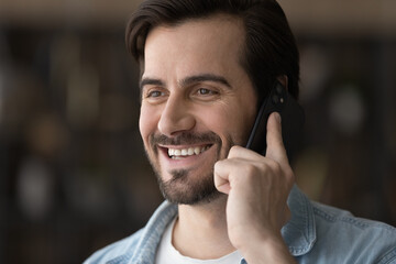 Glad to hear. Happy millennial male listen to praise good news share success personal achievement in phone conversation. Optimistic young guy talk by telephone receive gratitude from satisfied client - obrazy, fototapety, plakaty