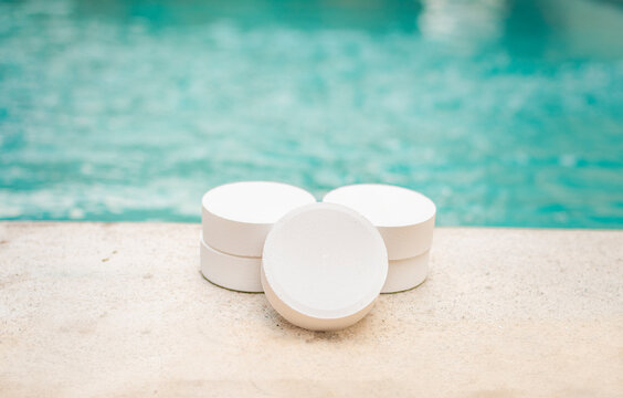 Close-up of some chlorine tablets for cleaning on the edge of a swimming pool, chlorine tablets to clean swimming pools, concept of chlorine tablets to disinfect swimming pools