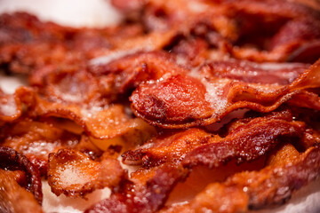 Macro view of appetizing, tasty, fried, crispy bacon slices, close-up, meat ham to scrambled eggs, shallow depth of field