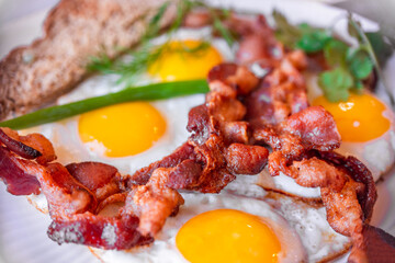 Tasty fried eggs eggs and crispy bacon, close-up, great classic breakfast. Macro photography, shallow depth of field.