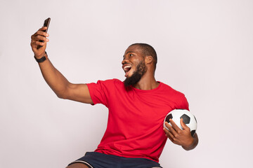 excited black man holding a football and checking his phone