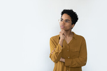 Young thoughtful African woman staring aside at copy space advertising text, looks pensive, feels...
