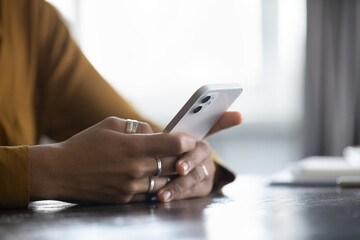 Close up cropped view African female hands holding smartphone seated at table, spend time use e-date services for singles, mobile app usage, young gen and modern wireless tech, gadget overuse concept