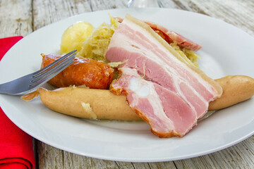 sauerkraut garnished with bacon sausages and a potato on a plate