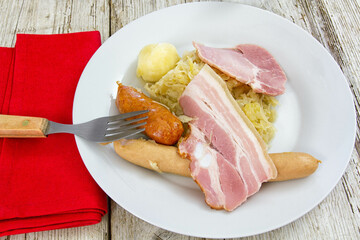 sauerkraut garnished with bacon sausages and a potato on a plate