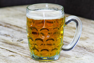 mug of beer with foam on a wooden background