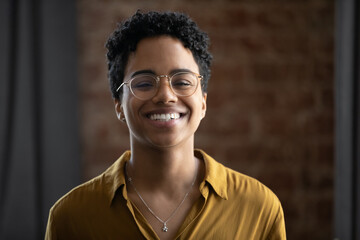 Attractive African woman in glasses having wide charming smile stand alone indoor pose for camera, head shot portrait. Eyesight, vision correction, eyewear store and dental clinic services ad concept