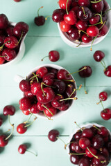 Delicious cherries in white ceramic cups on a light green wooden table