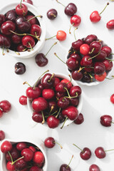 Delicious cherries in white ceramic cups on a white wood table