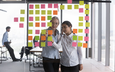 Multiracial young older women colleagues workmates prepare plan writing ideas and thoughts use...