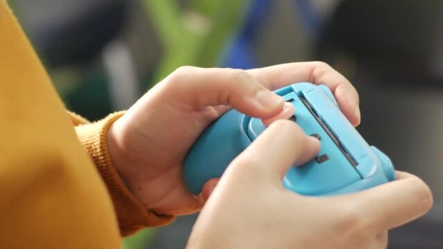 Close up of female hands playing digital video games and the Nintendo Switch gaming wireless controller.