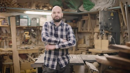 A brutal and bald man in a carpentry workshop. Craftsman at work.