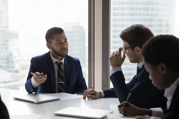 Indian businessman executive participate in meeting with clients sit at desk talk to partners, solve current business, discuss contact details, customer and company representative negotiations concept