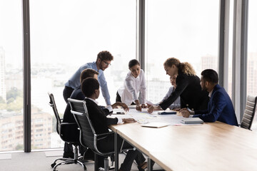 In modern boardroom diverse business team discuss project reports, develop marketing strategy,...