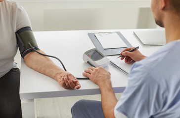 Doctor at clinic checking arterial pressure of older woman. Senior lady diagnosed with hypertension...