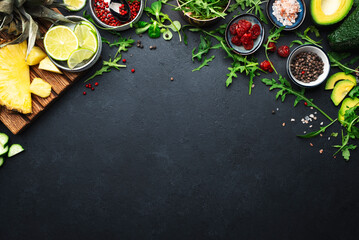 Healthy eating food layout and diet nutrition concept. Pineapple, vegetables, fruits, greens and other ingredients for salad preparation on black table background, copy spaсe