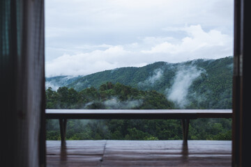 A wooden terrace with greenery rainforest mountains and hills on foggy day in background