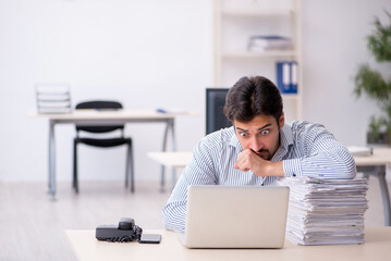 Young male employee and too much work in the office