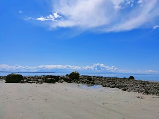 Fototapeta na wymiar Rocks near beach under blue sky